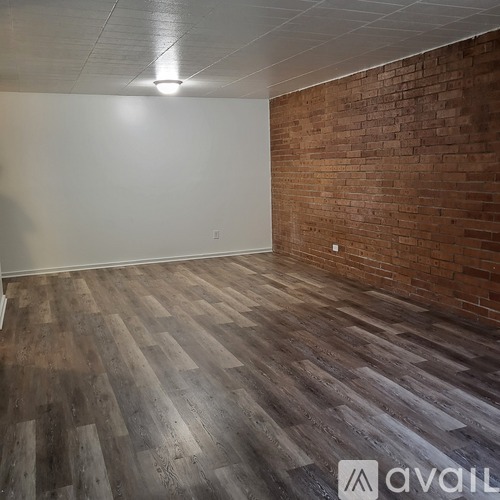 A room with wooden flooring and a brick wall.