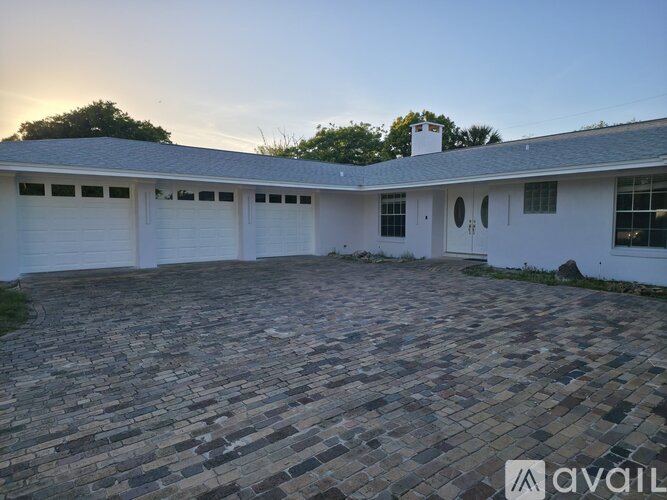 A house with a white exterior and a grey roof with a garage door.