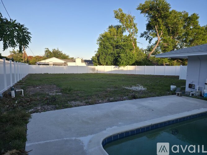 A backyard with a pool and a house in the background.