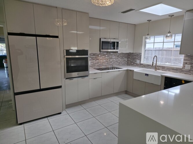 A kitchen with white cabinets and a stone backsplash.