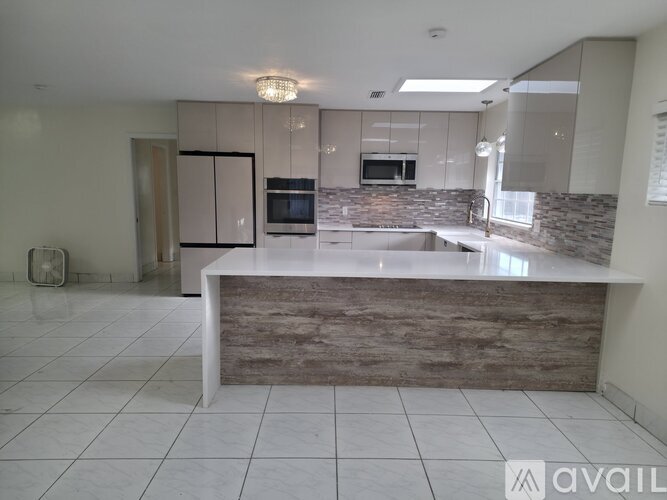 A kitchen with a stone backsplash and a white island.
