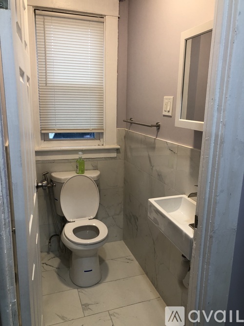 A bathroom with a toilet, sink, and window.