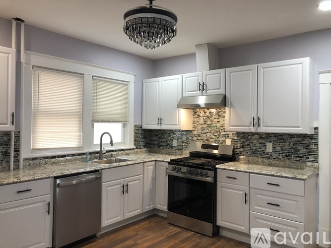 A kitchen with white cabinets and a stone backsplash.