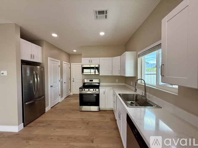 A kitchen with white cabinets and a stainless steel refrigerator.