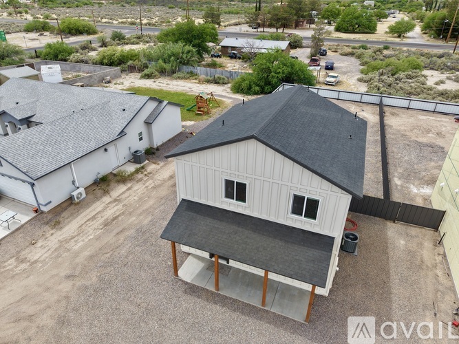 A house with a grey roof and a white exterior is surrounded by a gravel driveway.