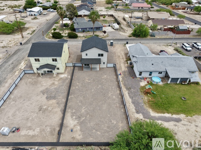 A large, empty lot with a house and a pool in the background.