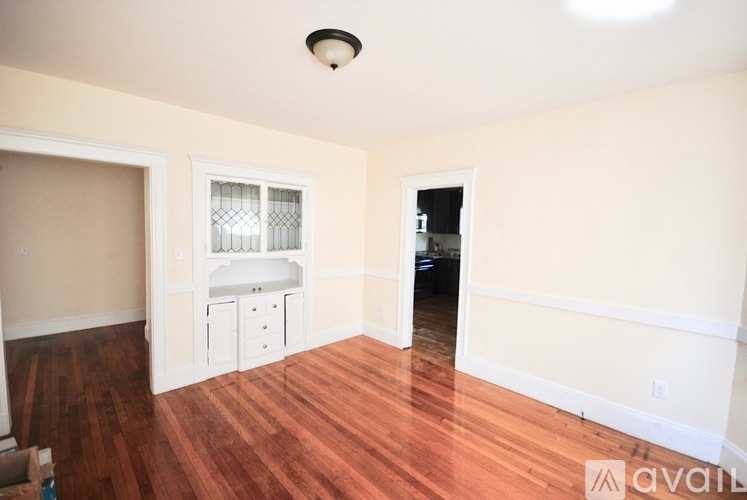 A room with wood flooring and a window with blinds.