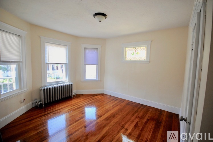 A room with wooden floors and a window with blinds.
