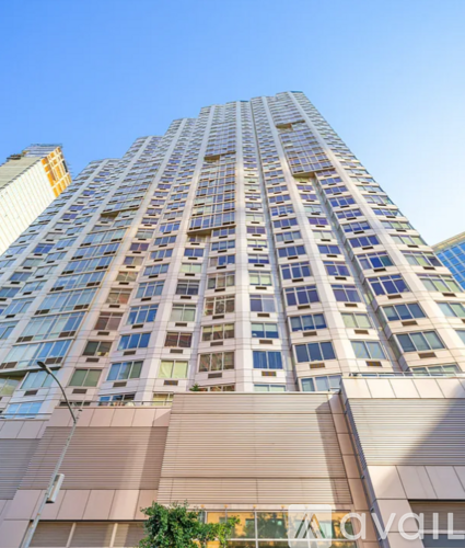 A tall building with many windows is seen against a clear sky.