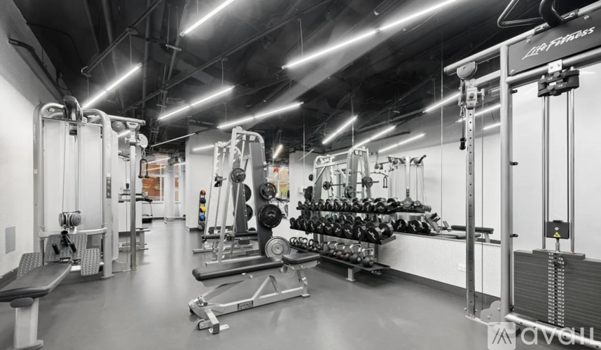 A gym with a variety of equipment including dumbbells and weight machines.