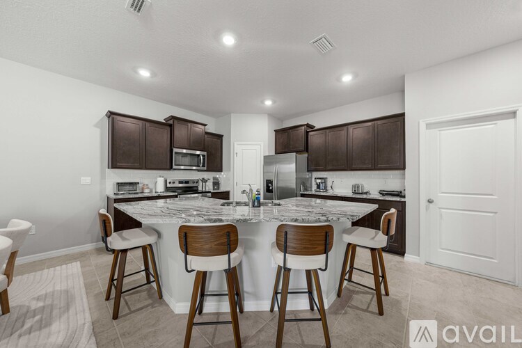 A kitchen with brown cabinets and a white island with four barstools.