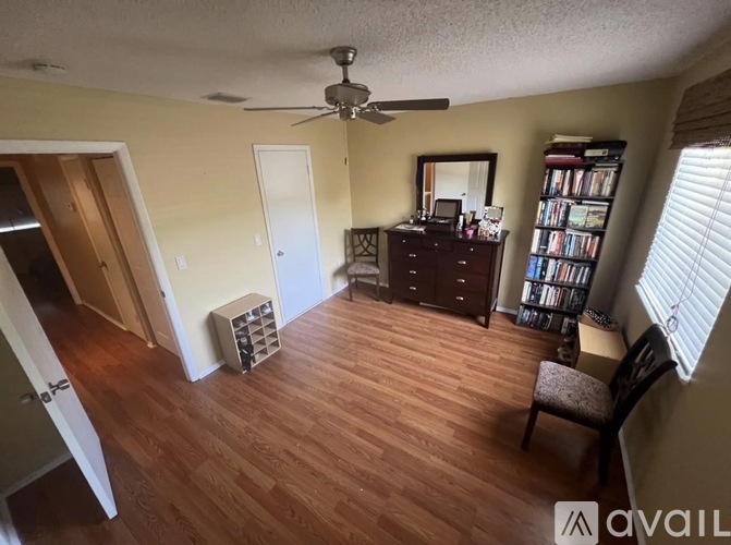 A room with a ceiling fan and a wooden floor.