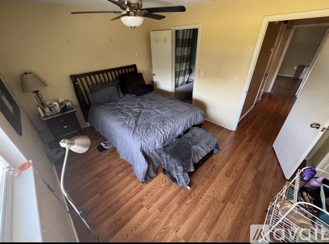 A bedroom with a bed, nightstand, and a ceiling fan.