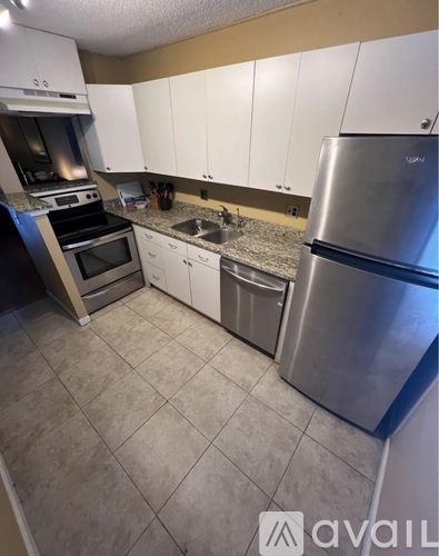A kitchen with white cabinets and a stainless steel refrigerator.
