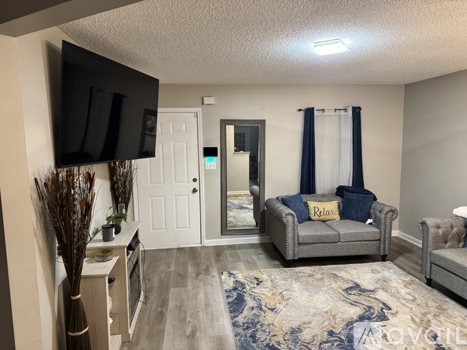 A living room with a grey couch and a television on the wall.