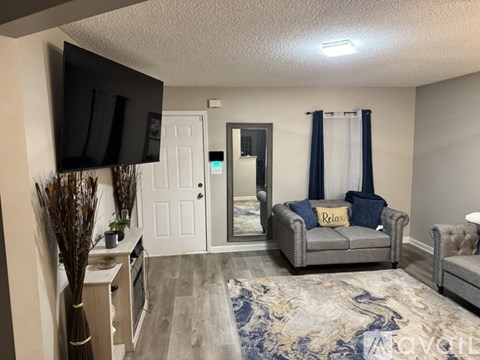 A living room with a grey couch and a television on the wall.