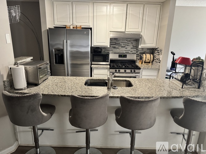 A kitchen with a granite countertop and grey chairs.