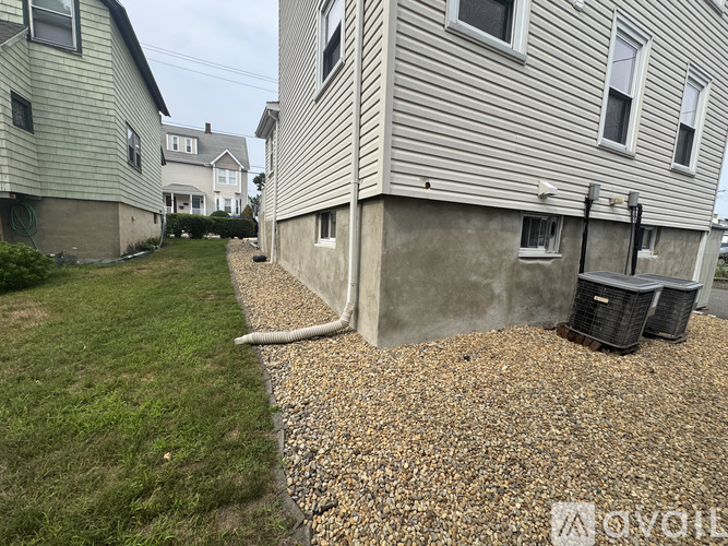 A house with a grey siding and a gravel area in front.