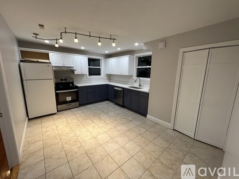 A kitchen with white cabinets and a refrigerator.
