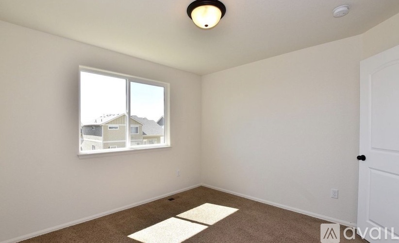 A room with a window showing a view of buildings outside.