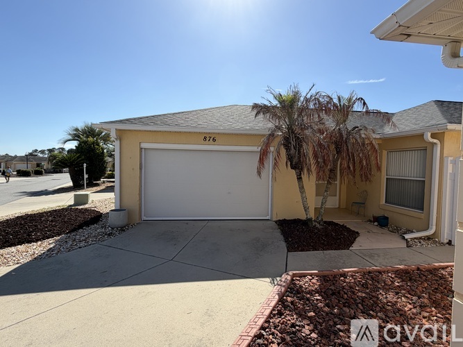 A house with a garage and a tree in front.