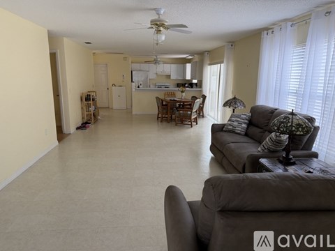A living room with a grey couch and a fan on the ceiling.