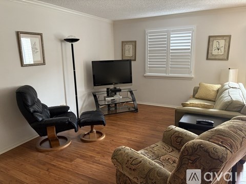A living room with a black chair and a brown couch.