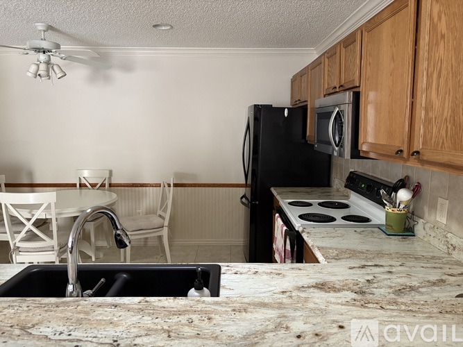 A kitchen with a black refrigerator and a white sink.