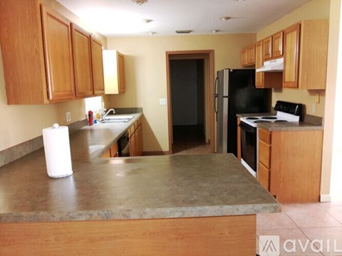 A kitchen with wooden cabinets and a black refrigerator.