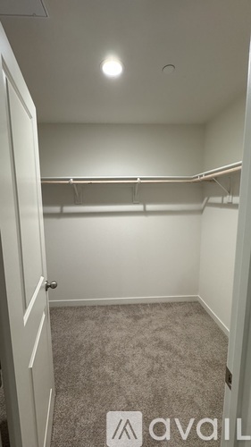 A small, empty room with a carpeted floor and a door on the left.