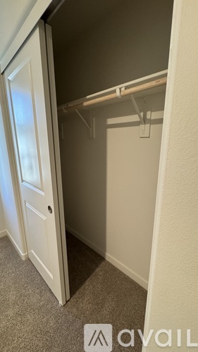 A small closet with a white door and a shelf above it.