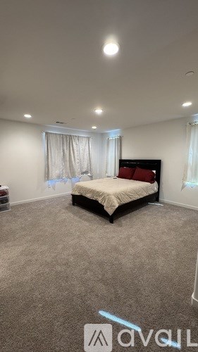 A bedroom with a bed, carpet, and a window.