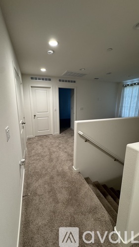 A hallway with a carpeted floor and a white door.