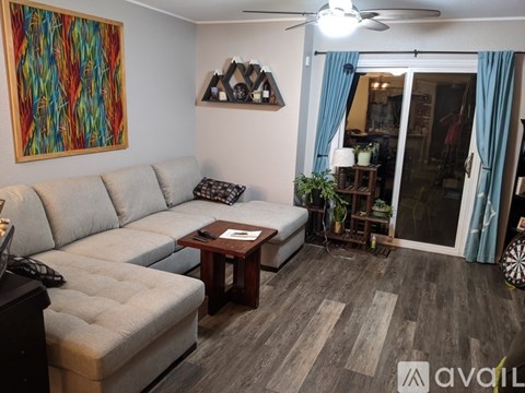 A living room with a grey couch, a coffee table, and a painting on the wall.