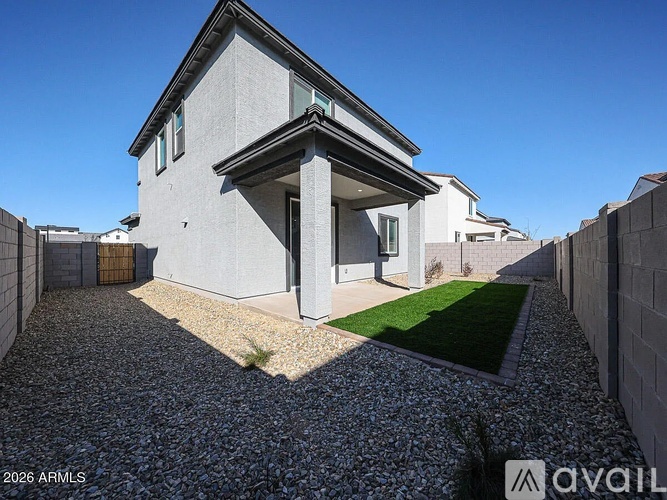 A modern house with a gravel driveway and a small grassy area.