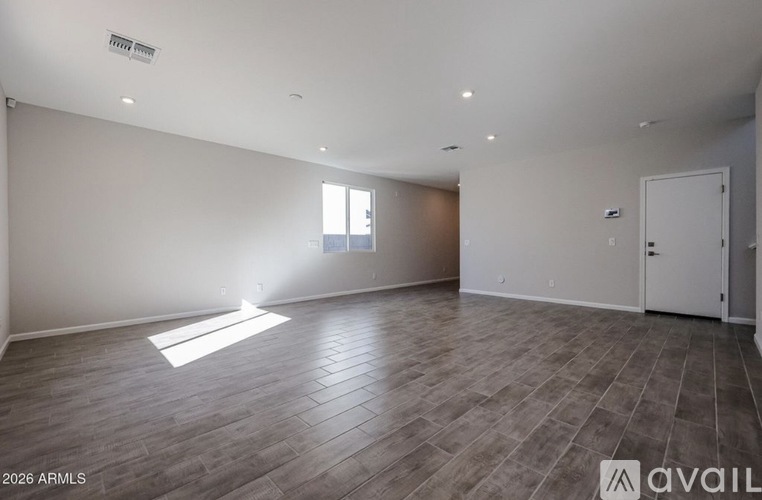 A spacious room with wooden flooring and white walls.