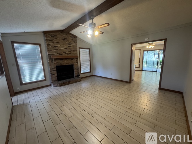 A living room with a stone fireplace and a ceiling fan.