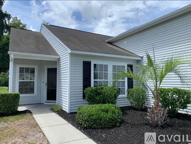 A small white house with a brown roof and a sign that says "AVAILABLE" in front of it.