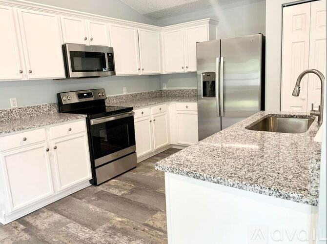 A kitchen with white cabinets and a granite countertop.