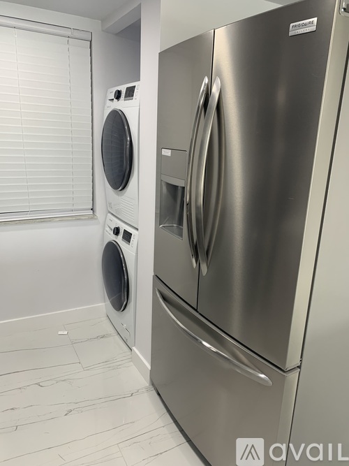 A stainless steel refrigerator and washing machine in a kitchen.