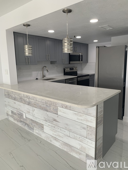 A kitchen with a white counter top and wooden backsplash.