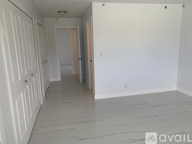 A hallway with white doors and a marble floor.