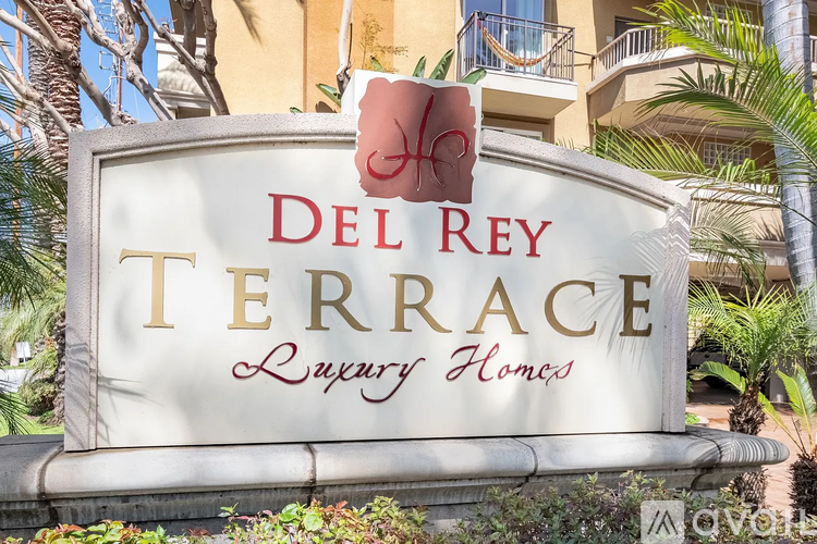 A sign for Del Rey Terrace Luxury Homes is displayed in front of a building.