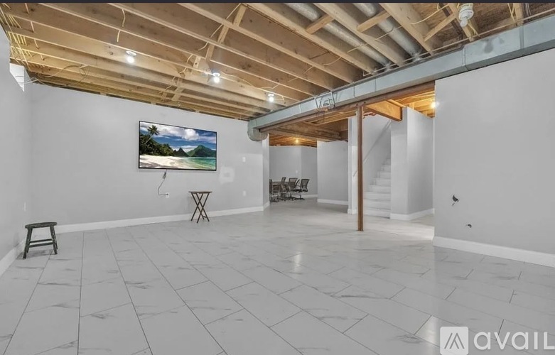 A spacious room with a painting on the wall and a wooden beam ceiling.