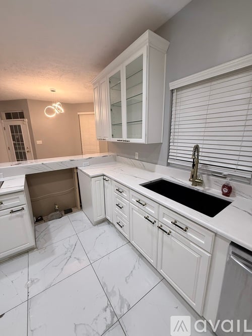 A kitchen with white cabinets and a black sink.