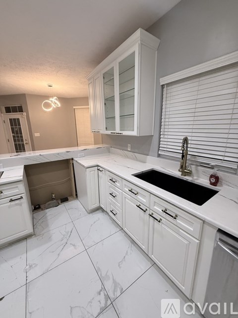 A kitchen with white cabinets and a black sink.
