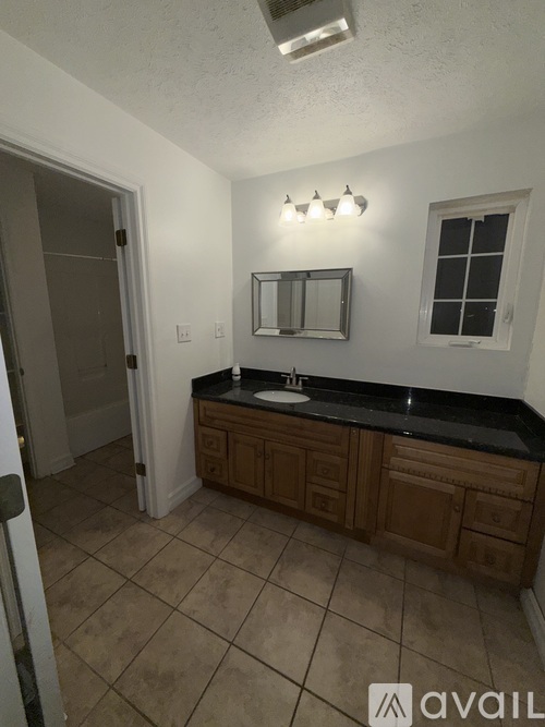 A bathroom with a sink, mirror, and tiled floor.