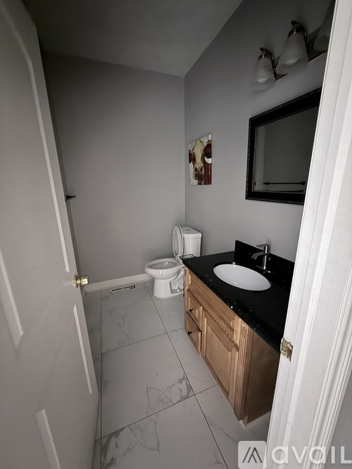 A bathroom with a toilet, sink, and mirror.