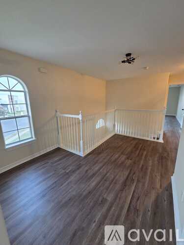 A room with wooden floors and a window with a white railing.