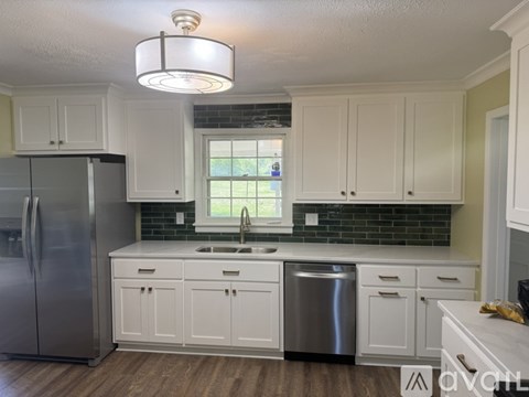 A kitchen with white cabinets and a stainless steel refrigerator.
